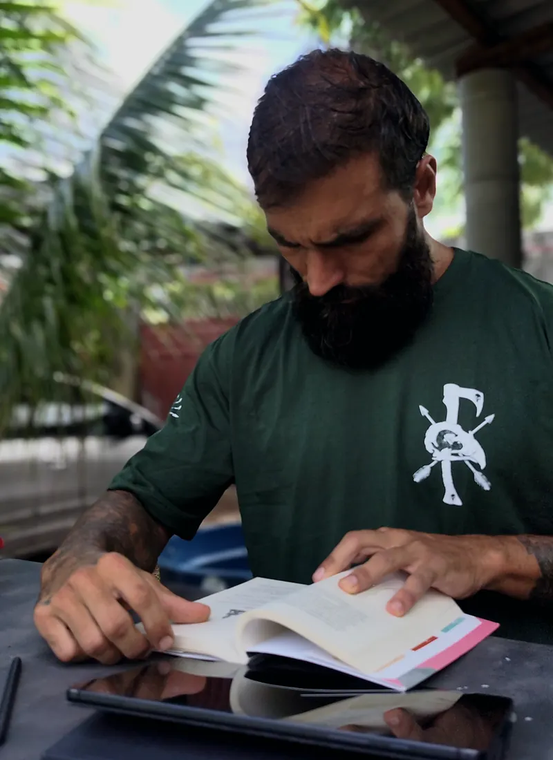 Diego Carvalho estudando, com livro e tablet sobre a mesa